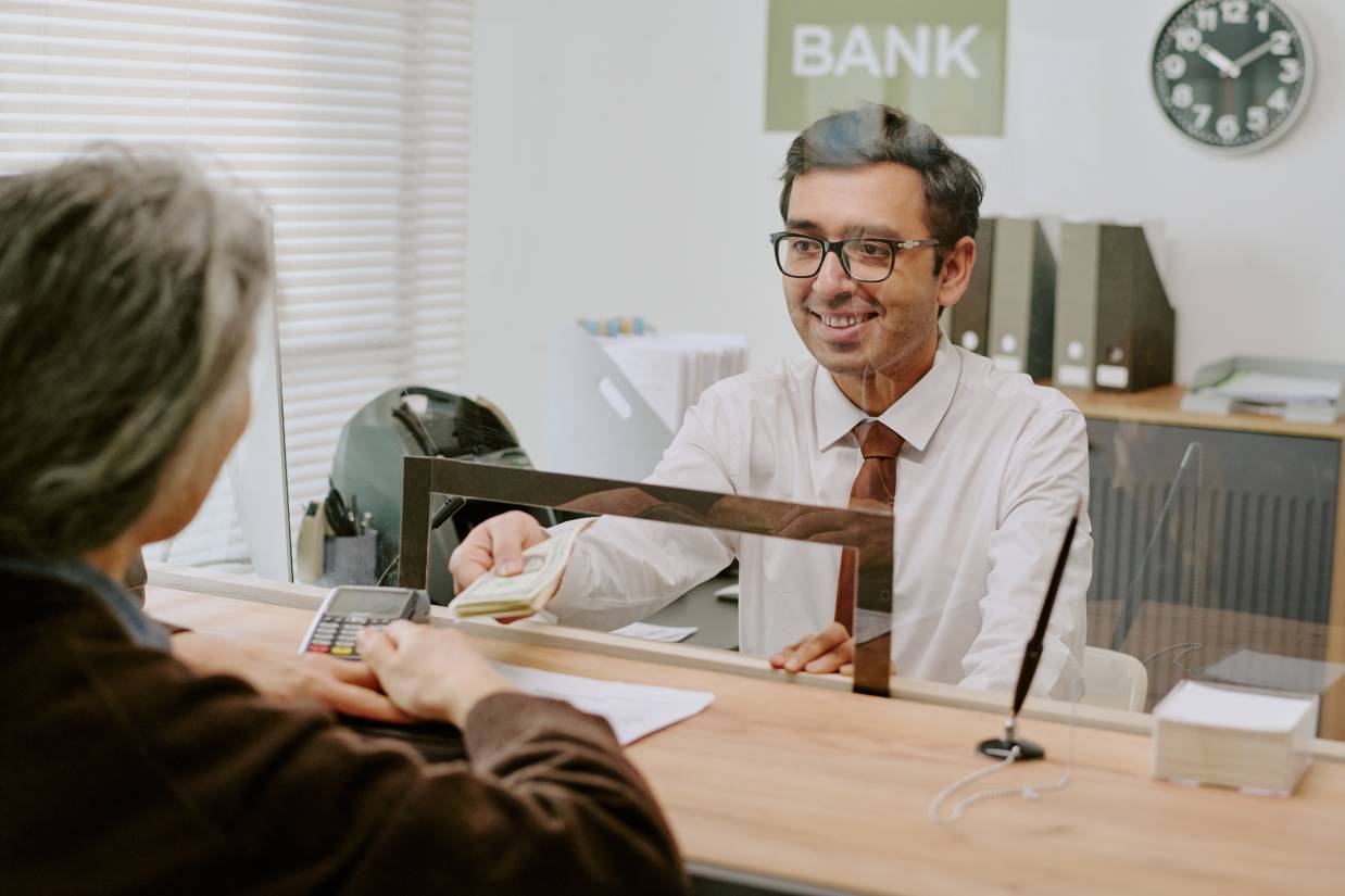 Bankschalter l&auml;chelt beim Helfen von Kunden