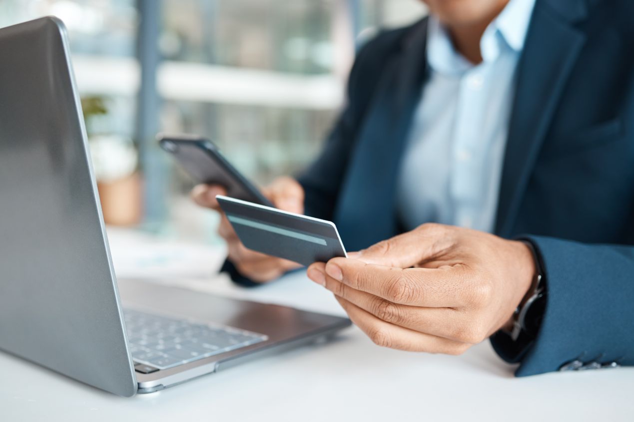 Businessman holding and using a credit card and phone alone at work