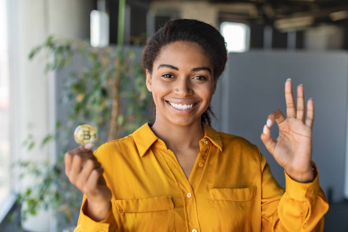 Businesswoman holding bitcoin and showing ok gesture