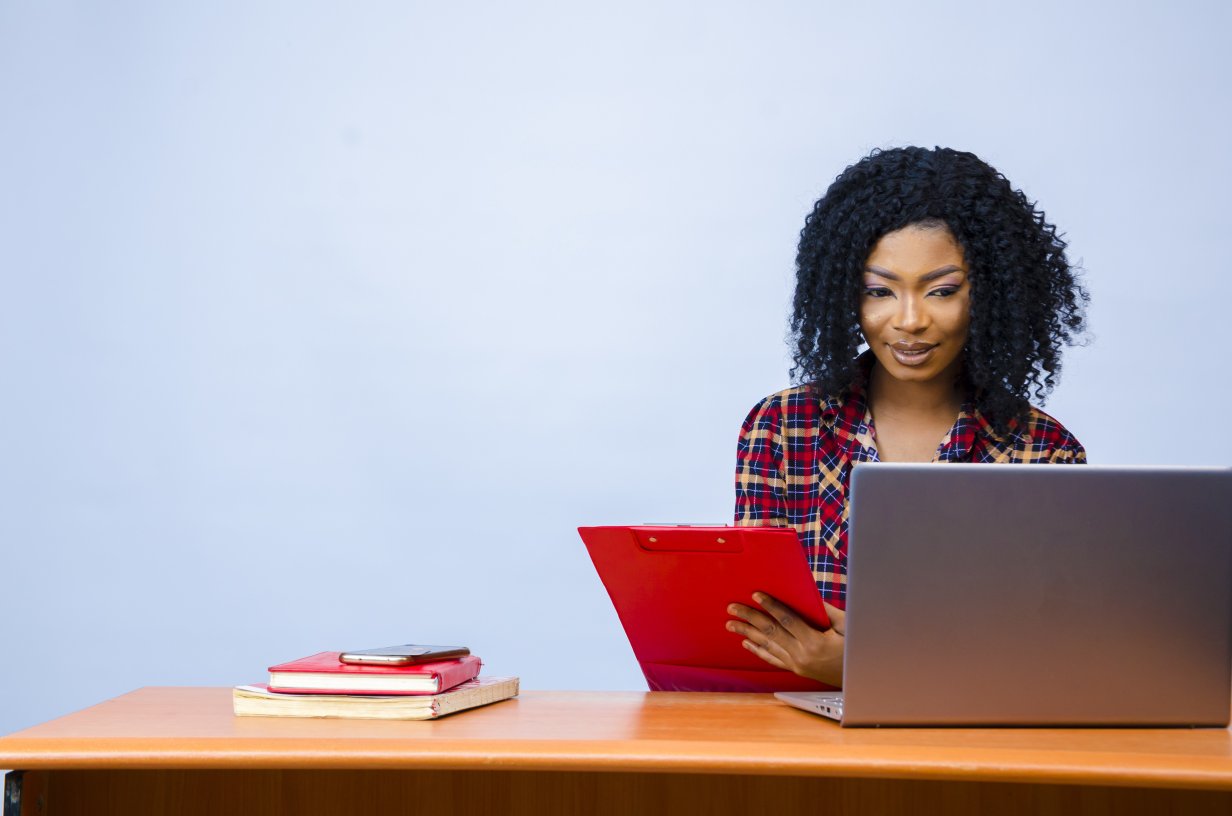 Female sitting in front of a laptop with a folder in her hands