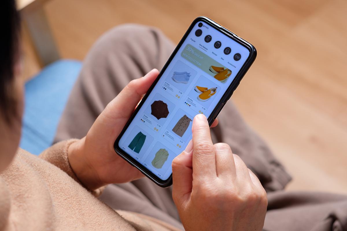 Hand browsing shopping fashion mobile app - one of the benefits of a digital wallet