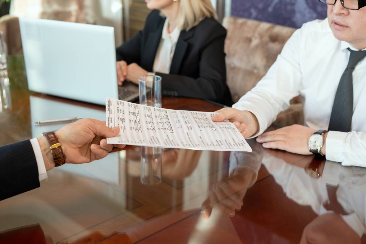 Hand of male delegate passing document with financial data to business partner