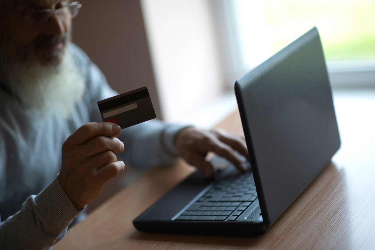 Man sitting at the laptop computer and holding credit bank card