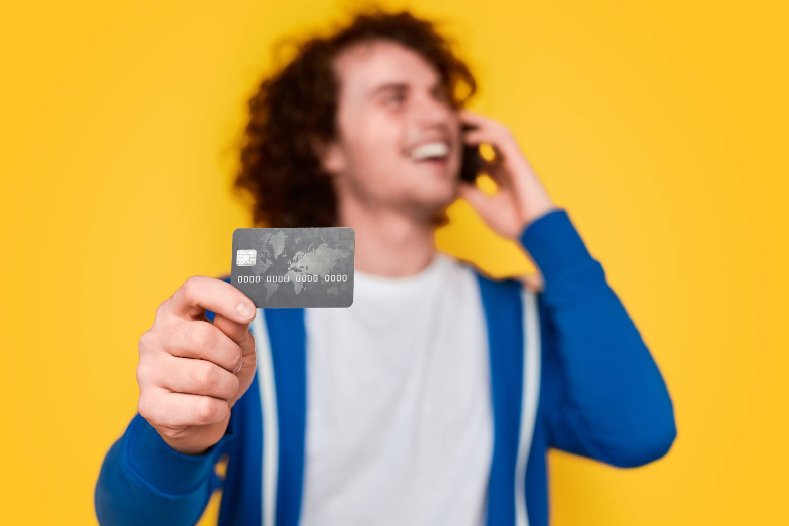 Hombre hablando por tel&eacute;fono y mostrando tarjeta de cr&eacute;dito
