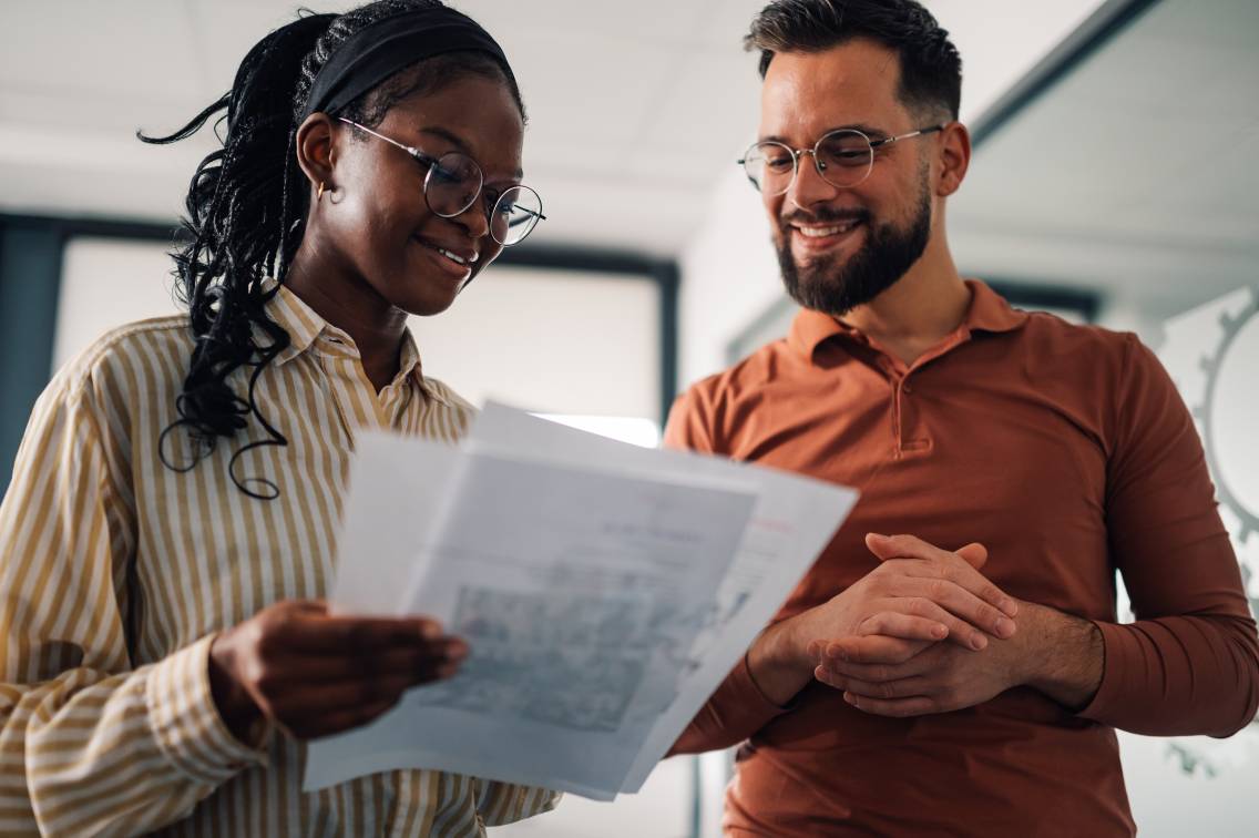 Smiling colleagues discussing documents in modern office