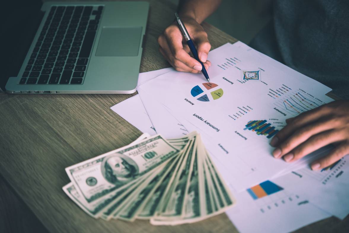 Table covered by cash notes, keyboard and financial charts