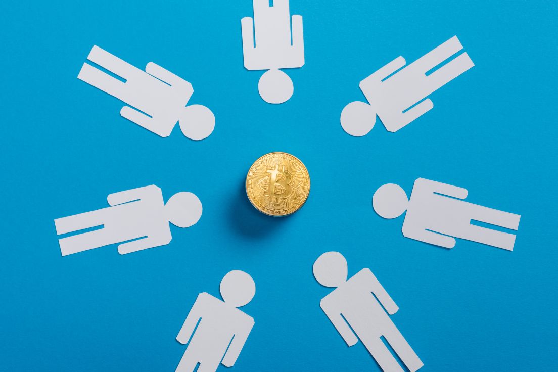 Draufsicht auf ausgeschnittene wei&szlig;e Menschen im Kreis neben goldener Bitcoin auf blauem Hintergrund