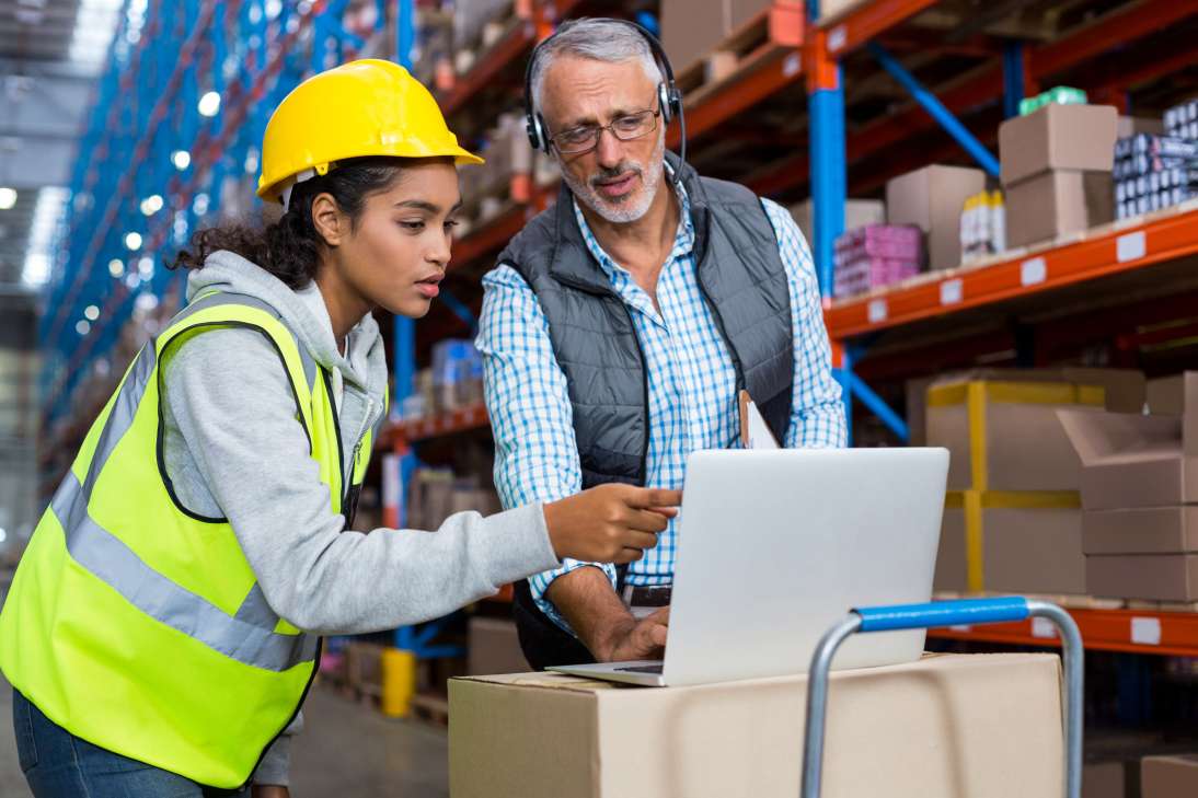 Responsable d'entrep&ocirc;t et travailleur f&eacute;minin utilisant un ordinateur portable